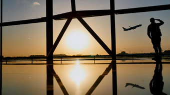 轮廓旅游的家伙看起飞飞机站机场窗口日落晚上旅行概念人机场