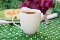 黑色的咖啡白色复杂的杯美味的饮食奶酪蛋糕自制的农民奶酪早餐花束紫色的郁金香绿色桌布