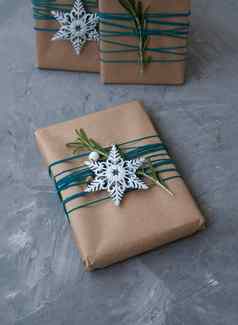 圣诞节礼物工艺纸包装蓝色的线程白色雪花迷迭香分支机构灰色的混凝土背景的地方文本