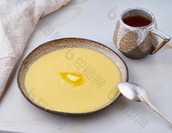 粥玉米粥黄油杯茶白色背景柔和的特写镜头