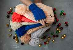 手年轻的美丽的女人蓝色的连指手套持有彩色的明亮的温暖的冬天帽子灰色的背景明亮的圣诞节装饰