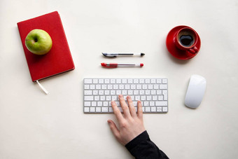 男人。手无线键盘红色的笔记本绿色苹果红色的杯咖啡白色表格