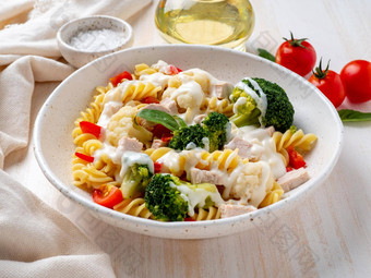 意大利面福西利蔬菜煮熟的蒸肉白色酱汁白色木表格低热量的饮食低脂饮食一边视图