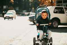 甜蜜的婴儿男孩巡回演出的演员自行车在户外孩子婴儿车婴儿孩子折叠式婴儿车春天走孩子们