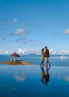 夫妇但女人看日落热带海滩毛里求斯棕榈树游泳池热带日落海滩毛里求斯