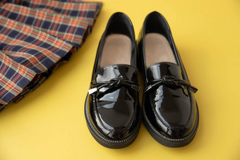 黑色的专利皮革休闲鞋格子苏格兰学校裙子黄色的背景