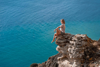 夏天生活方式快乐惊人的女人坐着岩石海享受生活海绿松石海背景红色的洗澡西装白色衬衫