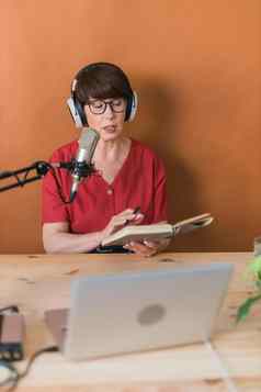 成熟的女人使播客记录在线显示有吸引力的业务女人耳机前面麦克风广播广播