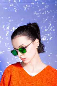 美丽的女孩橙色毛衣绿色眼镜蓝色的背景