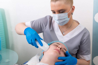 年轻的女人接收电电抗衰老脸水疗中心按摩美沙龙