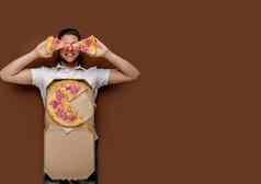 在线披萨安全交付服务餐厅年轻的有趣的快递男人。了棕色（的）背景傻瓜块披萨