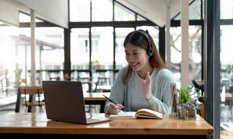 快乐年轻的女人耳机说话移动PC使笔记女孩学生<strong>会</strong>说话的视频<strong>会</strong>议调用女老师教练辅导网络摄像头在线<strong>培训</strong>e-coaching概念