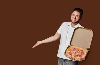 在线披萨安全交付服务餐厅年轻的惊讶快递男人。微笑点空空间做广告