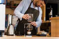 英俊的有胡子的咖啡师持有弯管设备手咖啡酝酿咖啡馆弯管替代方法使咖啡