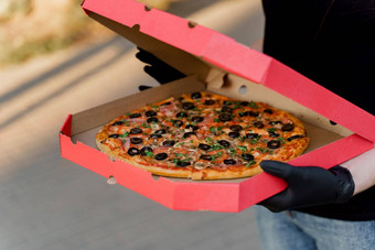 食物快递黑色的医疗手套持有红色的盒子披萨比萨 店食物交付检疫冠状病毒科维德期