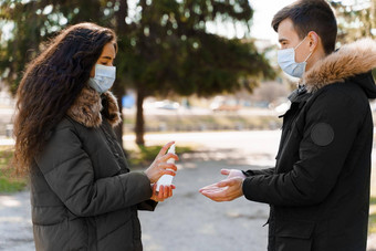 年轻的夫妇医疗面具防腐剂喷雾女孩喷雾的男朋友手停止冠状病毒科维德