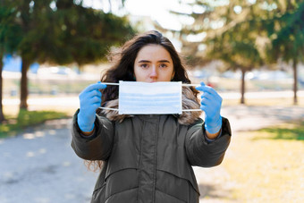 高加索人女孩显示无菌医疗面具蓝色的医疗手套保护冠状病毒科维德