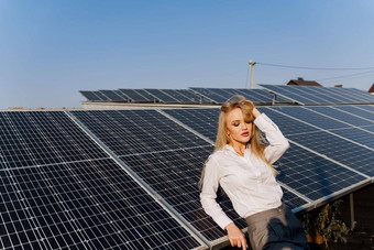 女人倾斜太阳能面板金发女郎穿着白色正式的衬衫权力植物免费的电首页绿色能源