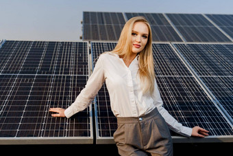 金发女郎模型太阳能面板站行地面女孩穿着白色正式的衬衫微笑权力植物绿色能源