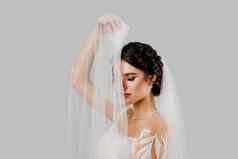 年轻的有吸引力的新娘婚礼衣服触摸新娘面纱白色背景工作室广告社会网络婚礼机构新娘沙龙