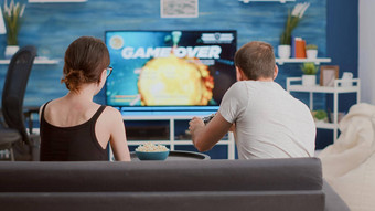 夫妇争论男人。失去在线游戏控制台前面大屏幕