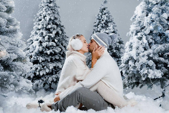 下降雪吻快乐年轻的夫妇特写镜头拥抱吻圣诞节树夏娃一年庆祝活动冬天一天笑脸男人。女人穿白色套头毛衣爱