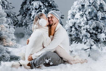 冬天爱故事夫妇穿皮毛耳机帽子白色毛衣快乐年轻的夫妇拥抱吻圣诞节树夏娃一年庆祝活动冬天一天