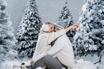 冬天爱故事夏娃一年庆祝活动夫妇拥抱圣诞节树冬天假期爱故事年轻的夫妇穿白色套头毛衣快乐男人。女人爱