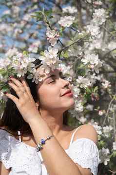 年轻的高加索人女人享受开花苹果树