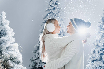 下降雪吻快乐年轻的夫妇特写镜头拥抱吻圣诞节树夏娃一年庆祝活动冬天一天笑脸男人。女人穿白色套头毛衣爱