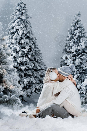 夫妇拥抱圣诞节树冬天假期爱故事年轻的夫妇穿白色套头毛衣快乐男人。年轻的女人爱