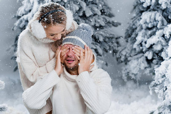 夫妇夫妇笑有趣的雪瀑布圣诞节树冬天假期爱故事年轻的夫妇穿白色套头毛衣快乐男人。年轻的女人拥抱