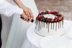 夫妇削减婚礼蛋糕草莓蓝莓前白色美味的蛋糕仪式广告厨师