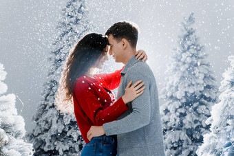 快乐年轻的夫妇拥抱吻圣诞节树夏娃一年庆祝活动冬天一天笑脸男人。女人爱下降雪吻
