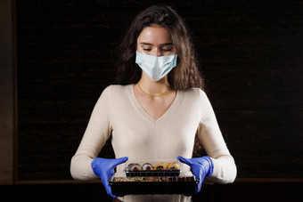 女孩寿司食物快递医疗面具交付检疫冠状病毒科维德年轻的女人持有寿司盒子手手套