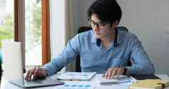 肖像年轻的亚洲男人。手自由职业者工作工作电脑平板电脑现代办公室会计分析报告真正的房地产投资数据金融税系统概念