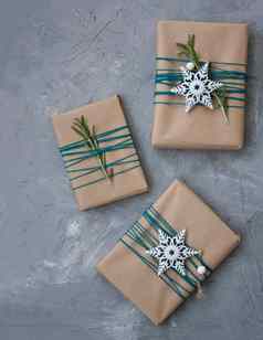 圣诞节礼物工艺纸包装蓝色的线程白色雪花迷迭香分支机构灰色的混凝土背景的地方文本