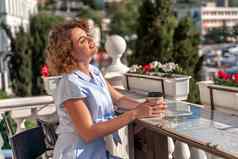 快乐美丽的女人喝咖啡牛奶健康的早餐户外咖啡馆夏天城市欧洲