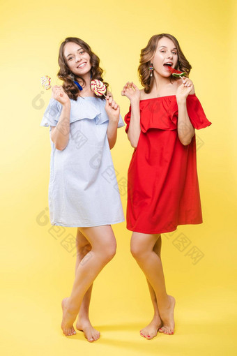 可爱的浅黑肤色的女人姐妹红色的蓝色的礼服黄色的背景