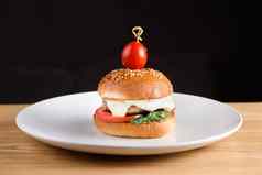 汉堡肉片酱汁番茄生菜芝麻白色板黑暗背景
