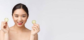 自然自制的新鲜的黄瓜面部眼睛垫面部面具亚洲女人持有黄瓜垫微笑放松自然自制的