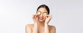 自然自制的新鲜的黄瓜面部眼睛垫面部面具亚洲女人持有黄瓜垫微笑放松自然自制的