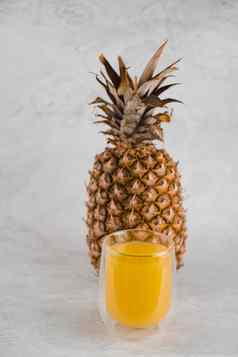 菠萝水果汁双玻璃杯白色石头背景倒黄色的热带水果汁玻璃
