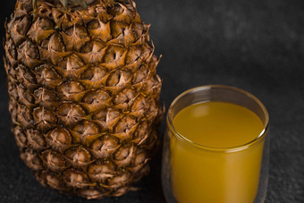 菠萝水果汁双玻璃杯黑色的石头背景倒黄色的热带水果汁玻璃
