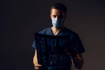 医生医疗面具保护冠状病毒科维德持有x射线扫描生病了病人通过电脑断层摄影术外科医生医疗袍图片扫描黑暗背景