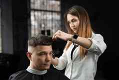 女人理发师使发型理发店限幅器理发师切割头发英俊的男人。