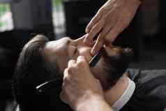 直剃须刀减少男人胡子理发店理发师男人。使发型英俊的男人。