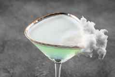 绿色酒精鸡尾酒玻璃装饰棉花糖果灰色的背景