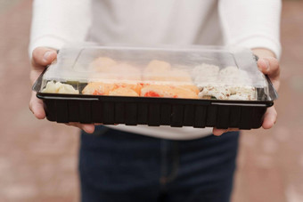 特写镜头寿司盒子健康的食物交付在线服务男人。白色衣服寿司集日本厨房卷我是酱汁芥末酱