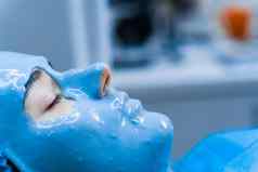 藻酸盐保湿面具脸皮肤年轻的女孩水疗中心过程复兴美容师涂片蓝色的面具皮肤病学医疗诊所